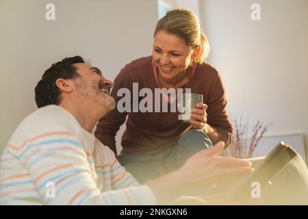 Happy woman talking to mature man gesturing at home Stock Photo