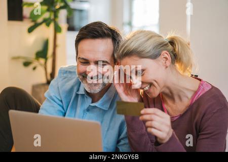 Happy couple doing online shopping through laptop at home Stock Photo