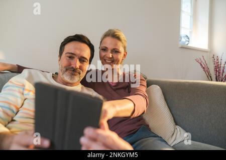 Smiling woman pointing at tablet PC held by man at home Stock Photo