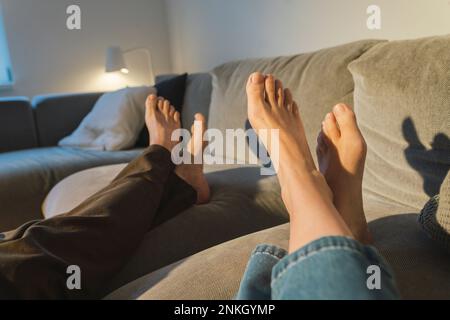 Couple's legs resting on sofa in living room Stock Photo