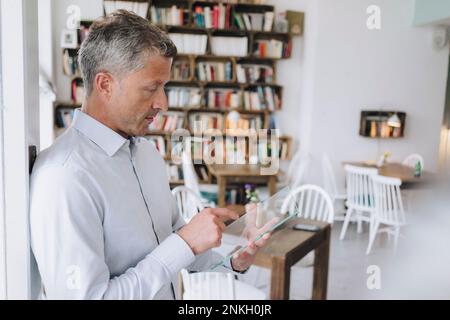 Businessman using futuristic transparent tablet PC in cafe Stock Photo