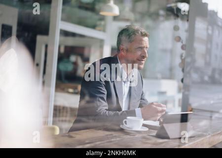Mature businessman having breakfast seen through glass in cafe Stock Photo