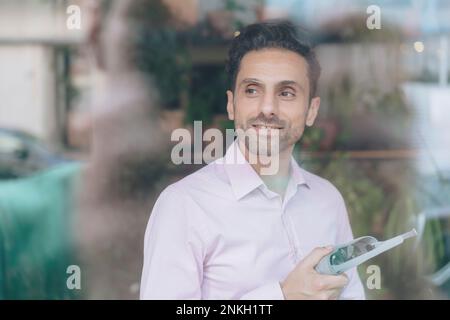 Smiling mature businessman with VR glasses seen through glass Stock Photo