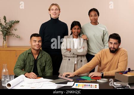 Confident multiracial fashion designers at desk in studio Stock Photo