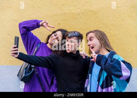 Young diverse friends taking selfies with a mobile phone outdoors. Stock Photo