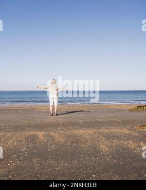 Elderly woman admiring sea at beach on sunny day Stock Photo