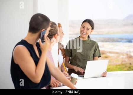 Happy businesswoman with laptop discussing with colleagues Stock Photo