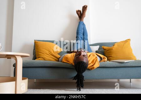 Man lying upside down on sofa at home Stock Photo