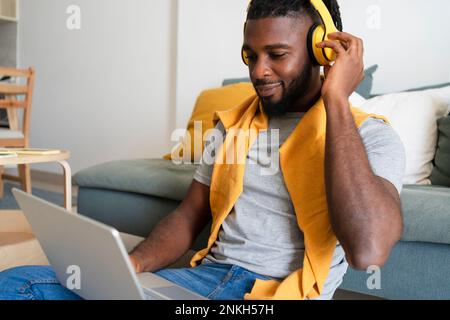Freelancer wearing wireless headphones working on laptop Stock Photo