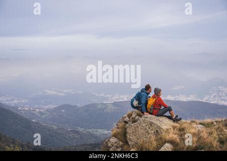 Mature man and woman sitting on rock Stock Photo