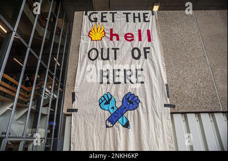 Delft, Netherlands, 22/02/2023, Ocean Rebellions activist leaves a taped large banner on the wall, and telling Shell during the 'DELFT CAREER DAYS 2023!'. Office workers at 'Allseas Engineering' received an impromptu concert from Ocean Rebellions heavy metal band 'Polymetallic Nodules' while using a boat as a stage. Songs were sang denouncing the engineering company with lyrics critical of the ocean mining industry and to the environmental damage caused by deep-sea mining. Allseas was one of the companies along with Deme-GSR at the 'DELFT CAREER DAYS 2023!'. Stock Photo