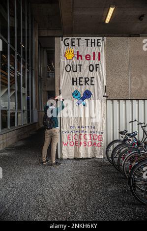 Delft, Netherlands, 22/02/2023, Ocean Rebellions activist leaves a taped large banner on the wall, and telling Shell during the 'DELFT CAREER DAYS 2023!'. Office workers at 'Allseas Engineering' received an impromptu concert from Ocean Rebellions heavy metal band 'Polymetallic Nodules' while using a boat as a stage. Songs were sang denouncing the engineering company with lyrics critical of the ocean mining industry and to the environmental damage caused by deep-sea mining. Allseas was one of the companies along with Deme-GSR at the 'DELFT CAREER DAYS 2023!'. Stock Photo