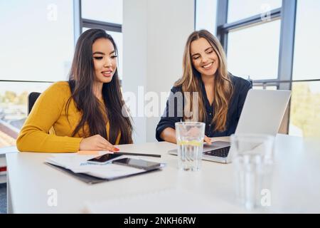 Smiling business colleagues working together over laptop at workplace Stock Photo