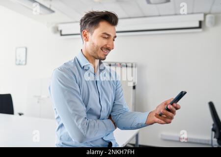 Smiling businessman using mobile phone at workplace Stock Photo