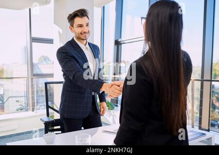 Smiling recruiter doing handshake with candidate after interview at office Stock Photo