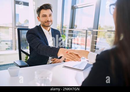 Smiling recruiter doing handshake with candidate at office Stock Photo