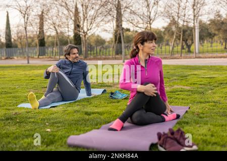 Mature man and woman doing yoga in park Stock Photo