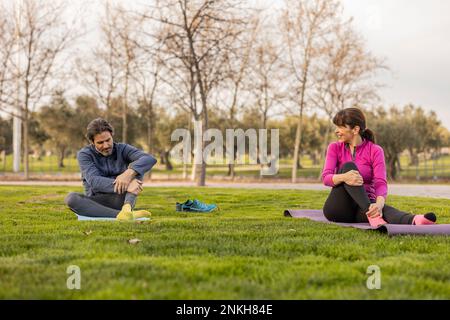 Happy mature couple practicing yoga in park Stock Photo