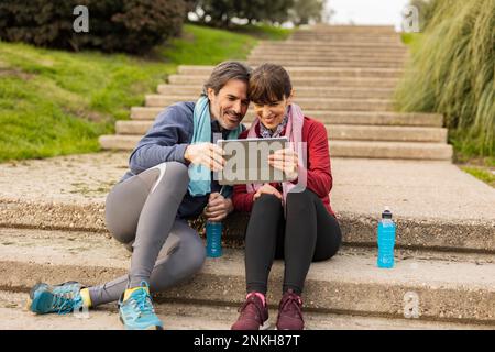 Happy mature couple using tablet PC on steps Stock Photo