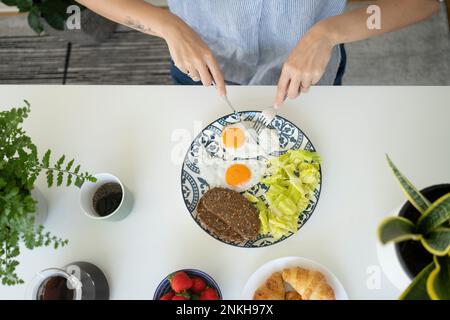 Woman having breakfast at table Stock Photo