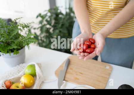 Woman holding cherry tomatoes in cupped hands at home Stock Photo