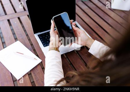 Freelancer using smart phone at table Stock Photo