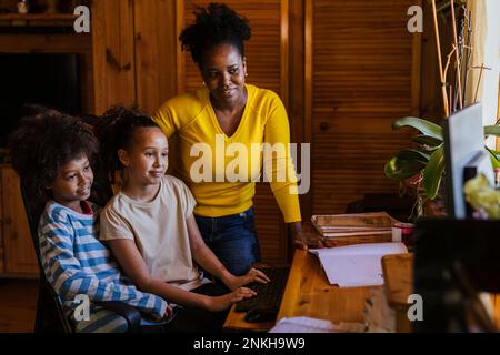 Smiling woman with son and daughter using computer at home Stock Photo