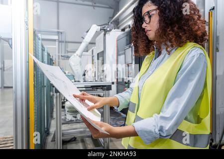 Young engineer examining blueprints in industry Stock Photo