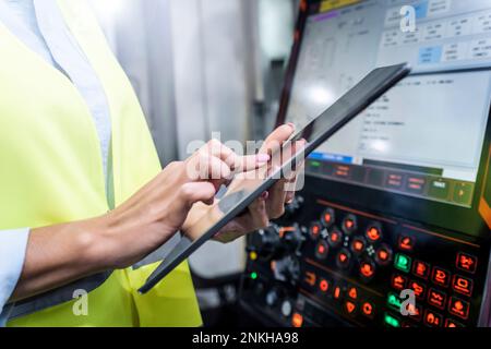 Hands of engineer using tablet PC by machine in industry Stock Photo