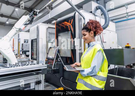 Happy engineer using laptop in factory Stock Photo