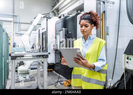 Engineer using tablet PC by machine in factory Stock Photo