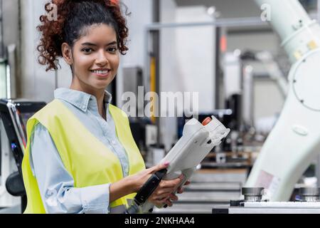 Smiling engineer standing with remote control in industry Stock Photo
