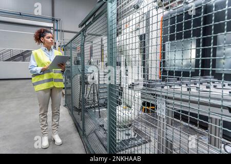 Young engineer using tablet PC by machine in industry Stock Photo