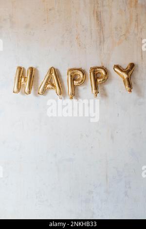 Happy text made with inflated balloons hanging on wall Stock Photo