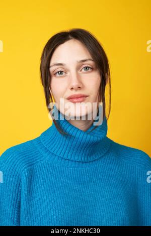 Young beautiful woman wearing blue turtleneck over yellow background Stock Photo
