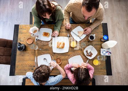Father and mother having breakfast with children at home Stock Photo