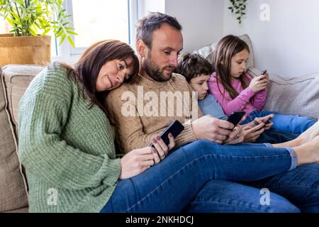 Man and woman with children using smart phone at home Stock Photo