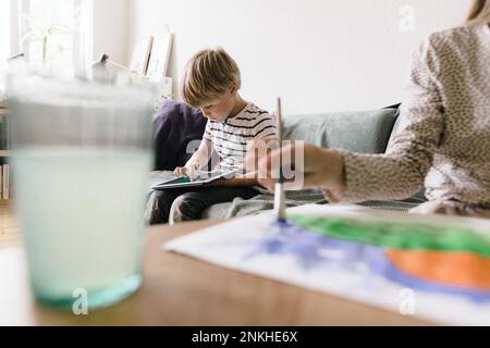 Boy using tablet PC sitting on sofa at home Stock Photo