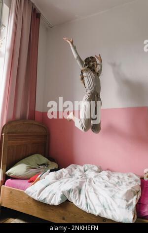 Carefree girl jumping on bed at home Stock Photo