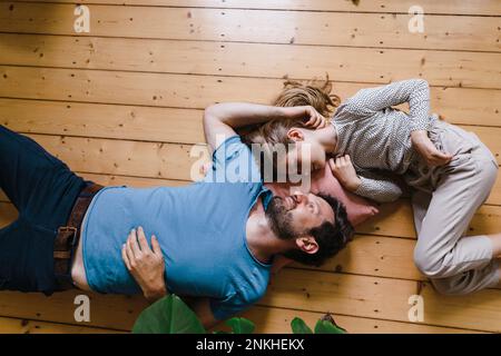 Daughter lying down with father on floor at home Stock Photo
