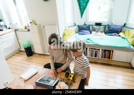 Girl using tablet PC by brother at home Stock Photo