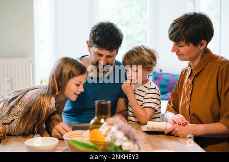 Family watching tablet PC together at dining table in home Stock Photo