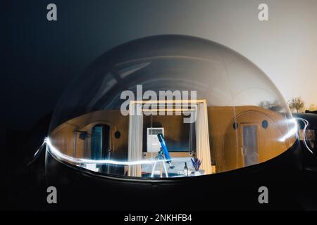 Telescope on tripod inside dome tent with light trails at night Stock Photo