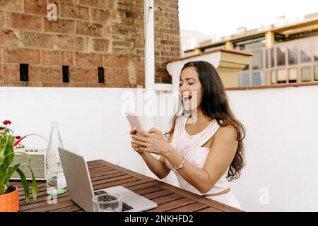 Surprised freelancer using smart phone at table Stock Photo