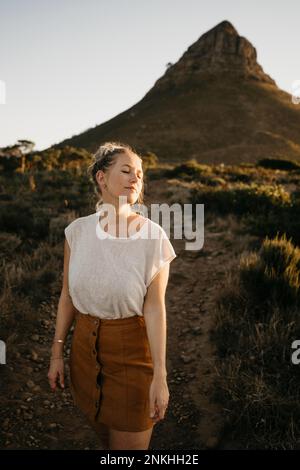 Woman enjoying sunlight in front of Lion's Head Mountain at sunset Stock Photo
