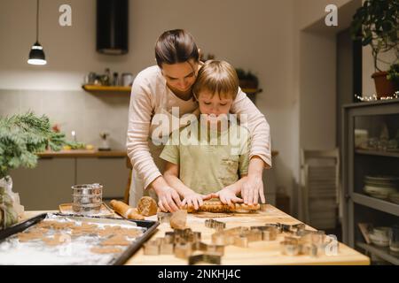 Mother and son making ginger cookies in kitchen at home Stock Photo