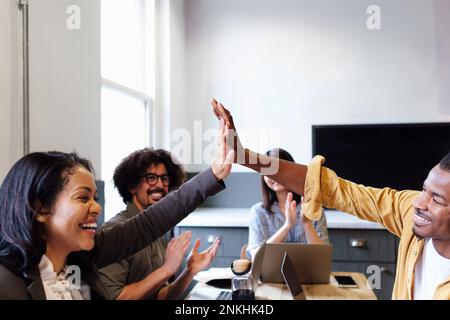 Cheerful business colleagues giving high-five to each other at office Stock Photo