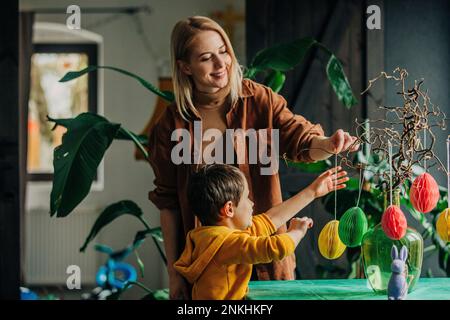 Happy mother and son decorating table for Easter dinner at home Stock Photo