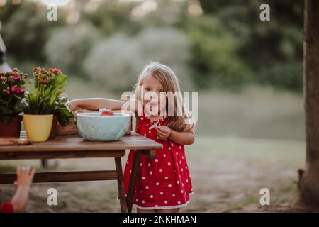 Cute girl picking up fruits from table Stock Photo