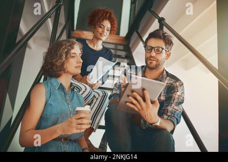 Where focus goes, energy flows. creative employees having a discussion on the staircase at work. Stock Photo